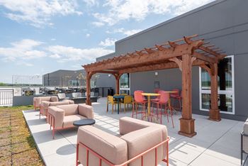 a patio with chairs and tables and a pergola on top of a building